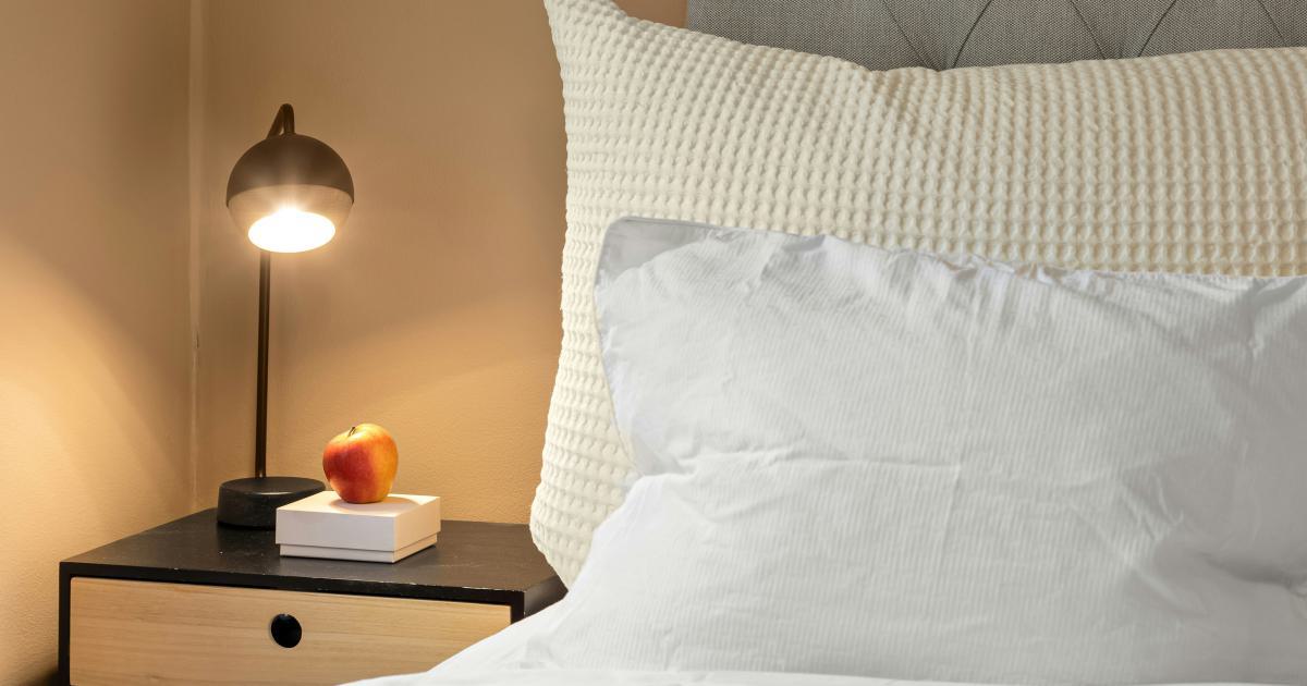Femme arrangeant son lit avec un oreiller ergonomique